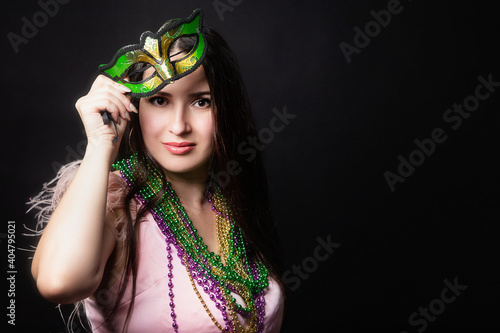 Mardi gras people. Woman with a carnival mask and beads on the black background with copy space