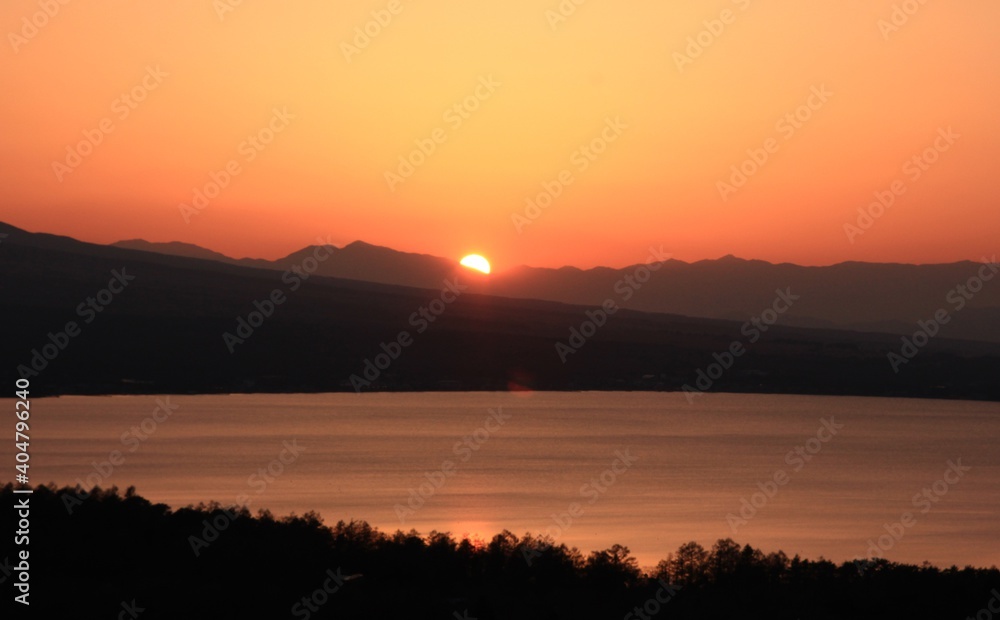 夕暮れの山中湖　　山中湖のの向こうに見える南アルプスに沈むオレンジ色の夕日