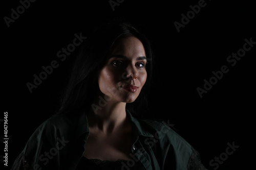 Portrait of beautiful young brunette woman on black background