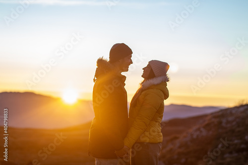 Portrait of a young couple in love holding hands at the mountain sunset.