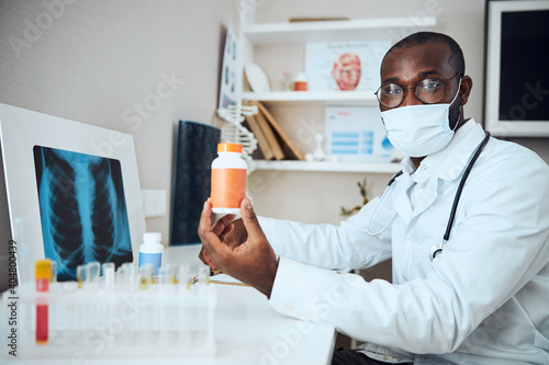 Mixed-race physician advertising pills in orange bottle