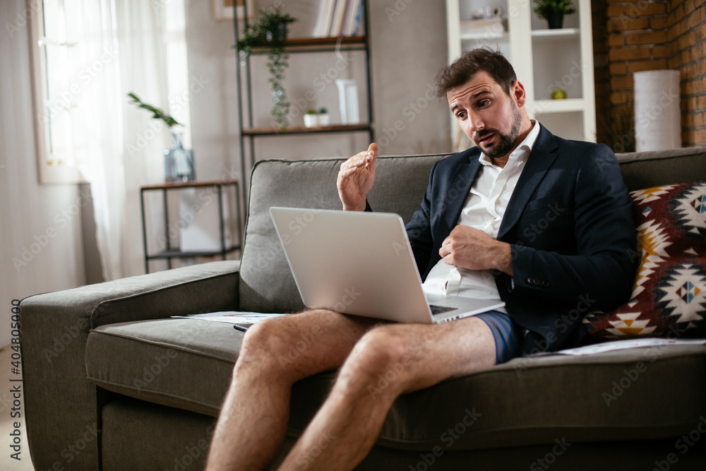 Businessman working online, wearing suit and no pants. Young man having video call. Businessman working at home. Businessman working online, wearing suit and no pants. Young man having video call. Businessman working at home.