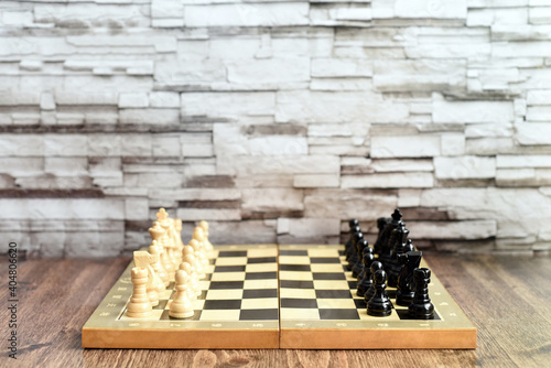 Chess pieces on chess board on wooden table. Blurred background with copy space