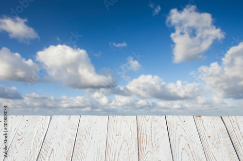 Empty white wooden table in front of a blurred background of some clouds ( cumulus ) . selective focus . space for copy and text. can be used to display or assemble your products.
