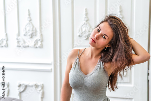 Portrait of a young brunette woman in a tight top on the background of white doors in a bright interior
