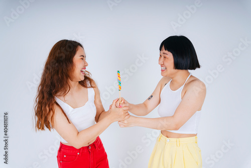 Asian women wearing white vest holding rainbow candy lollipop isolate on white background.