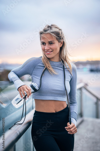 young active woman smiling after working out outside with her water bottle