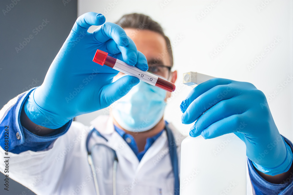 Doctor or scientist holds in one hand laboratory test tube with blood and clean place for text or inscription of analysis or pathogen, and in other plastic bottle with an antiseptic Doctor or scientist holds in one hand laboratory test tube with blood and clean place for text or inscription of analysis or pathogen, and in other plastic bottle with an antiseptic