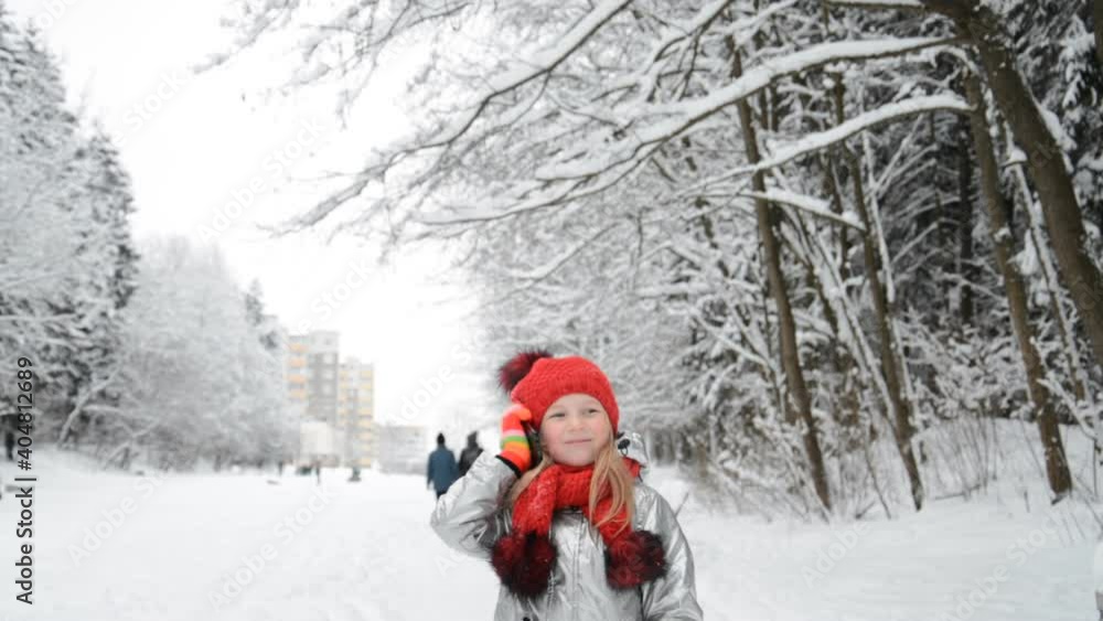 Little girl in a red hat talking on the phone in a winter park Little girl in a red hat talking on the phone in a winter park