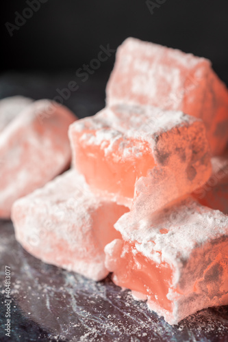 Top view of Turkish Delight of roses, stacked, with sugar on blue marble, selective focus, vertical