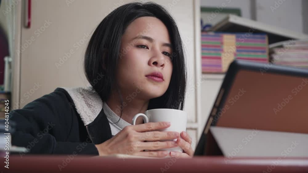 asian woman drinking hot beverage, holding white coffee cup, watch tablet on relaxing night at home, study at home learning online wireless technology, digital media learning online entertainment asian woman drinking hot beverage, holding white coffee cup, watch tablet on relaxing night at home, study at home learning online wireless technology, digital media learning online entertainment