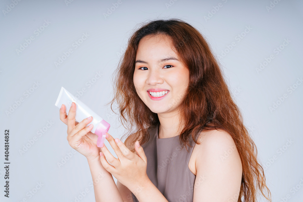 Asian curly hairstyle woman holding skincare cream lotion bottle isolate on white background. Asian curly hairstyle woman holding skincare cream lotion bottle isolate on white background.