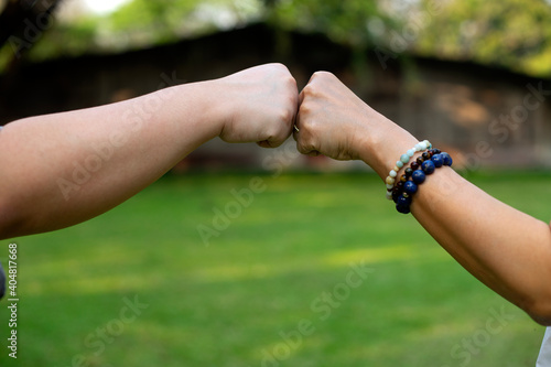 Close up image of two hand fist bump at the outdoor area green background © sabthai