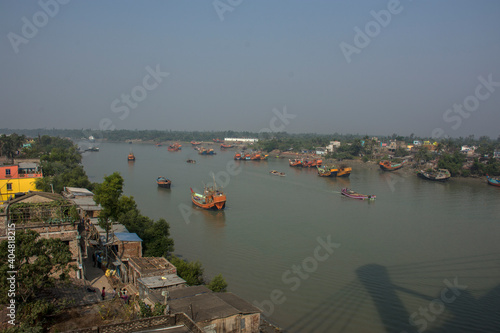 7th January, 2021. Namkhana, West Bengal, India. Colorful wooden fishing boats floating on matla river at Namkhana and few houses on the bank of river. photo