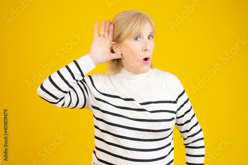 Senior woman with hand over ear listening and hearing to rumor or gossip. deafness concept.