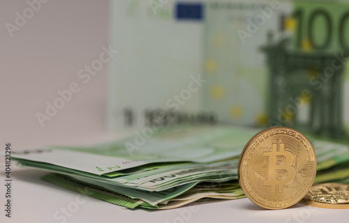 standing bitcoin with many 100 euro bills in the background