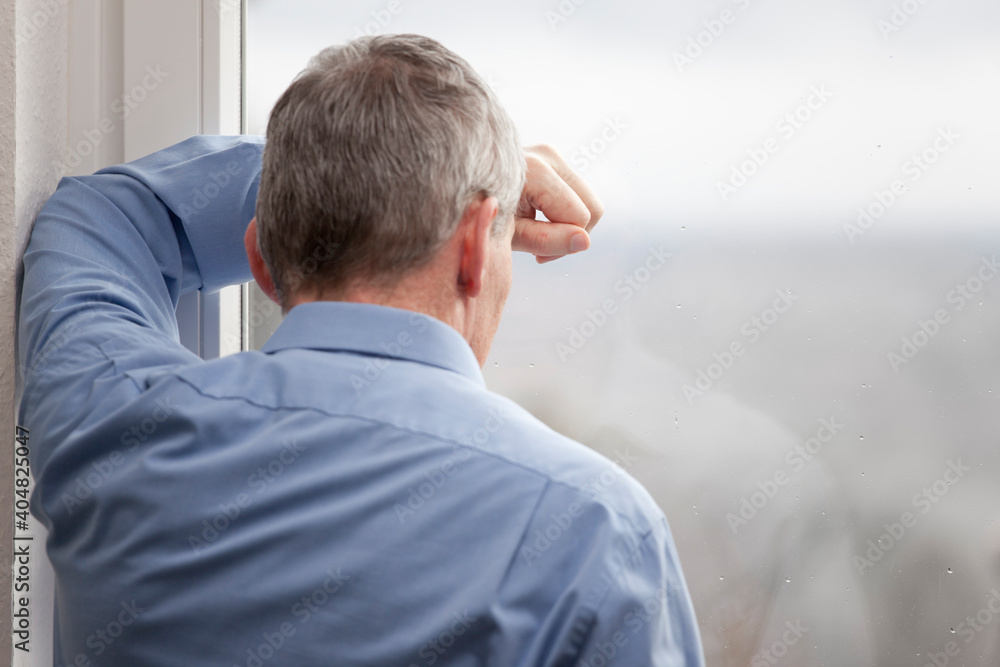 Tired or sorrowful businessman looking out of a window Tired or sorrowful businessman looking out of a window