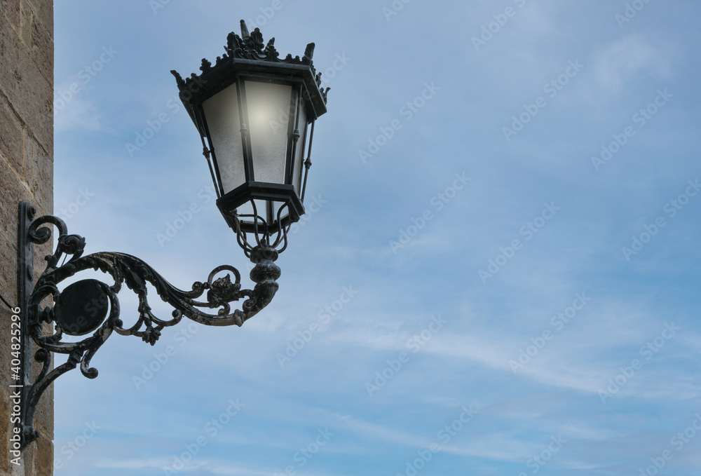 iron street lamp lit with blue sky background