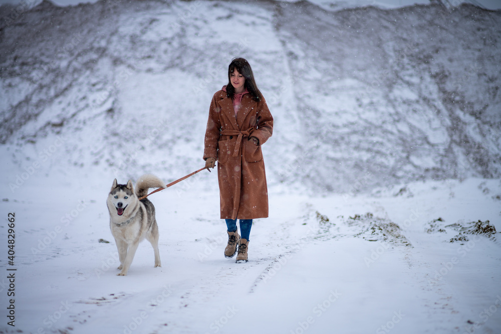 Girl with dog breed husky stands in winter park Girl with dog breed husky stands in winter park