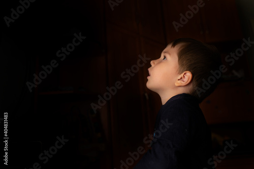 The face of a little boy on a dark background. Place for text