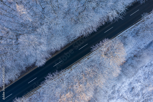 Csesznek, Hungary - Aerial top down view of winter forest crossed by asphalt road. Snowy landscape background. photo