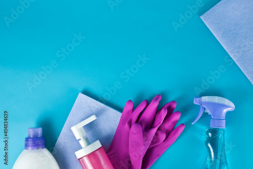 Washing rags with latex gloves, sprayer and soap in a dispenser on a blue background. Top view. Cleaning products and supplies concept.
