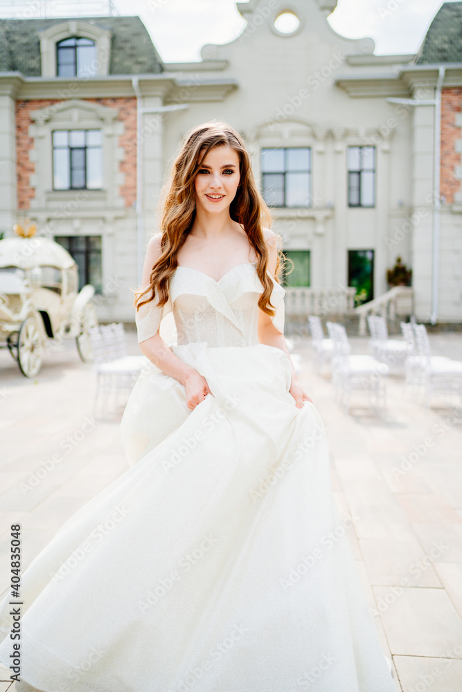 Obraz premium cheerful beautiful woman in white wedding dress whirls near beautiful building.