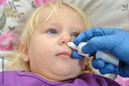 The doctor instills medicine into the nose of a small sick child. photo