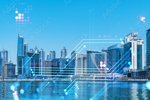 Skyscrapers of Dubai business downtown. International hub of trading and financial services. Technology theme icons hologram  Fintech concept. Double exposure. Dubai Canal waterfront.