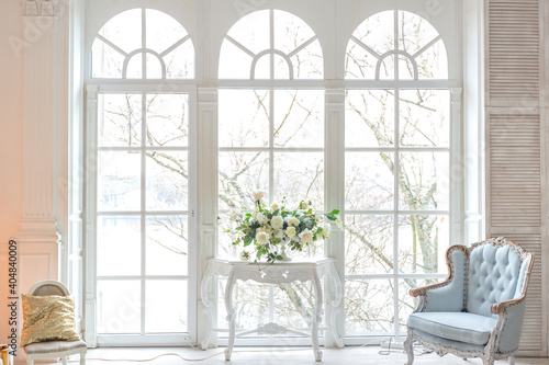 luxurious expensive light interior living room in a royal style decorated with a very beautiful Christmas tree and large windows