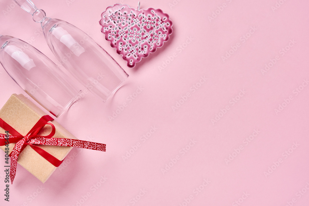 Two champagne glasses, a gift box, a beautiful serge and a red ribbon on a sparkling pink background. Valentine day greeting card. Top view.