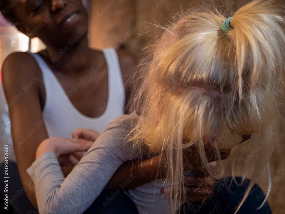Φωτογραφία African American woman in white bodysuit and jeans and Caucasian blond boy sing karaoke with microphone in their hands and fool around