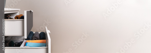 Vertical storage of clothing. Sorted clothes in baskets and shelves in a modern bedromm. Cleaning concept. Banner