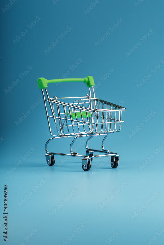 Empty shopping cart for goods from the supermarket on a blue background.