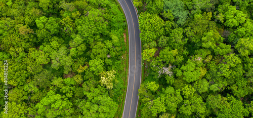 Winding road, top view of beautiful aerial view of asphalt road, highway through forest and fields in rainy season. For traveling and driving in nature. Banner panorama background. © Sunday Stock