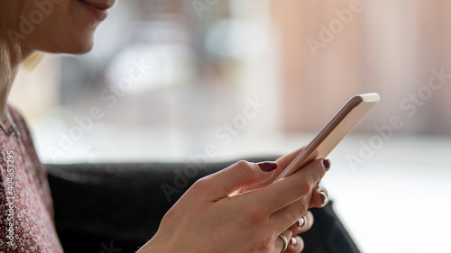 Junge Frau mit rot lackierten Fingern  geln h  lt ein Smartphone in der hand- Close view  Panoramaformat  viel Textfreiraum