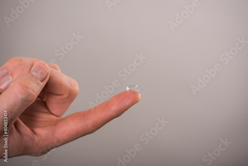 Close-up of a contact lens on a finger on a white background.