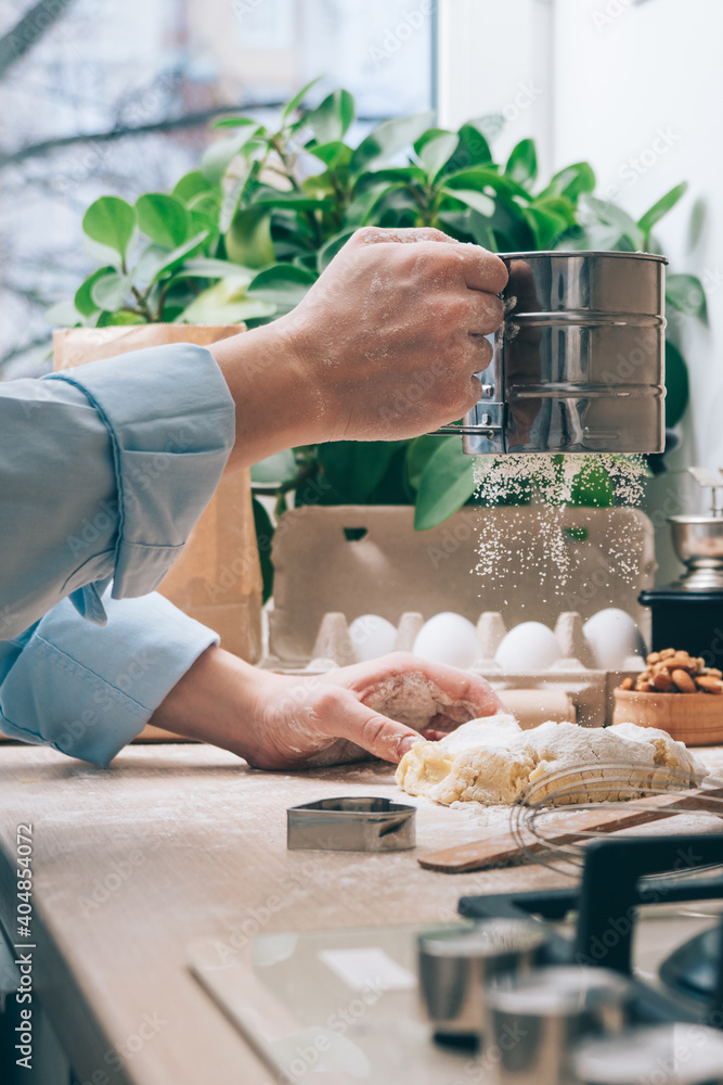 A girl without a face prepares dough, sprinkles it with flour, close-up. Cooking homemade cakes in the kitchen, at home. Culinary background A girl without a face prepares dough, sprinkles it with flour, close-up. Cooking homemade cakes in the kitchen, at home. Culinary background