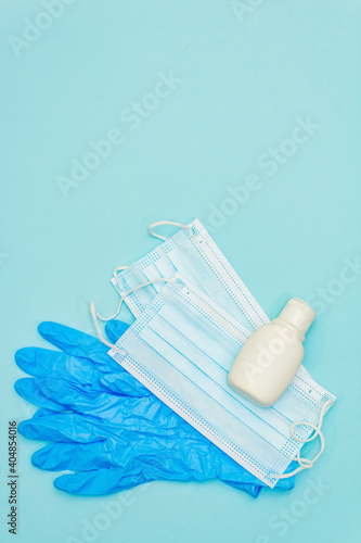 Medical protection masks, sanitizer and gloves isolated on light blue background