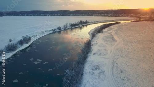 Wallpaper Mural Amazing winter landscape with red sunrise. The drone flies over the river at sunset. It's snowing. Natural reflection of the sunset in the water . On the horizon you can see a village, a city. Torontodigital.ca