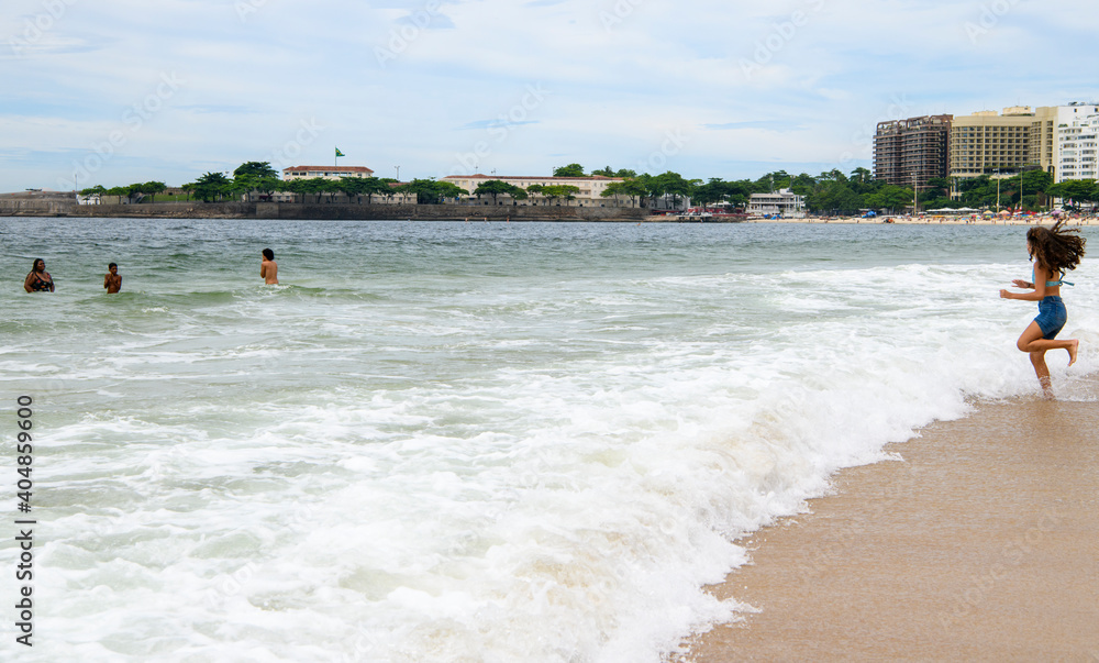  Vacationers swim in the ocean on the beach of Copacabana