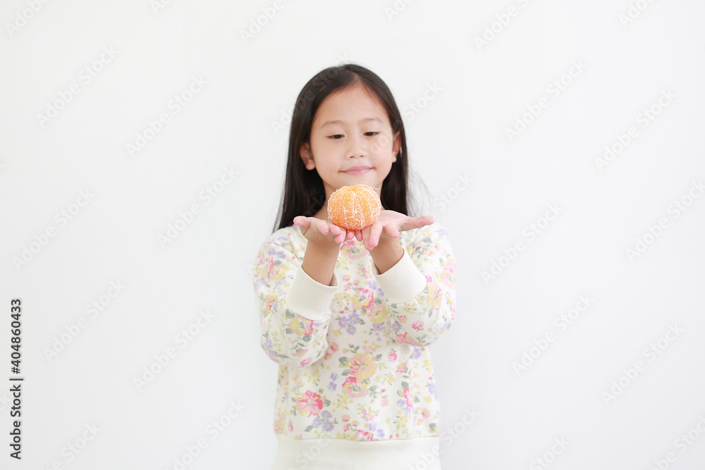 little asian girl holding peeled orange fruit on white background. Focus at orange in hands little asian girl holding peeled orange fruit on white background. Focus at orange in hands