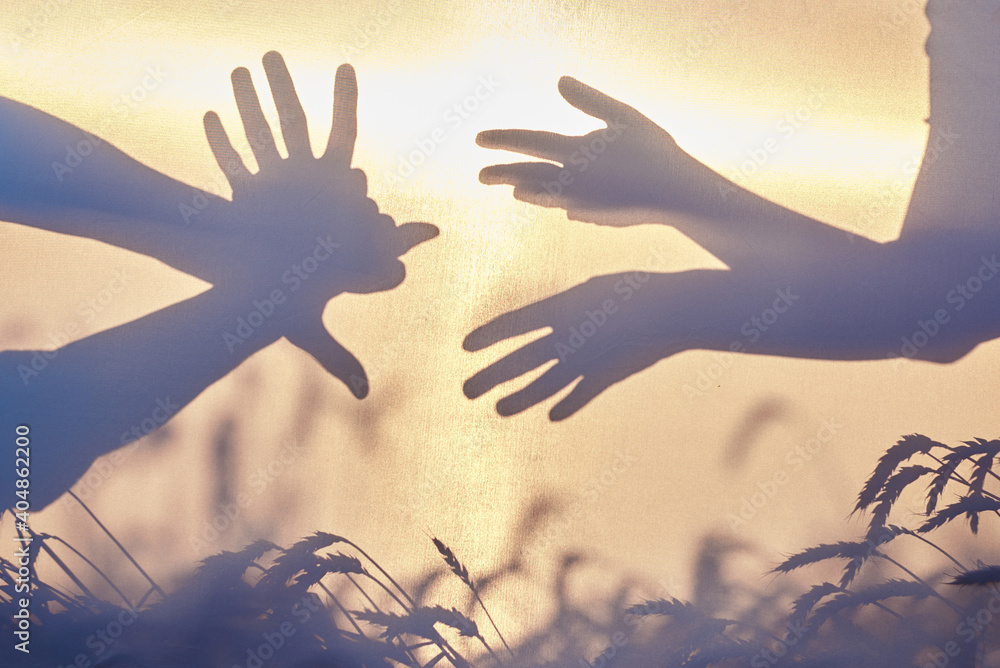 Shadow of male and female hands, showing monsters, fun creatures shapes in front of pale yellow sky at sunset. Shadow play with hands for children at natural background. Summer leisure entertainment. Shadow of male and female hands, showing monsters, fun creatures shapes in front of pale yellow sky at sunset. Shadow play with hands for children at natural background. Summer leisure entertainment.
