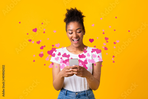 Black woman sending love message on cellphone, hearts flying away