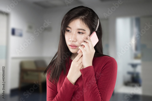 young asian woman pick up a cell phone with an anxious expression