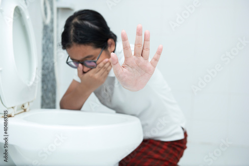 Close-up Of Asian young Woman Showing Stop Sign While Vomiting In Toilet Bowl