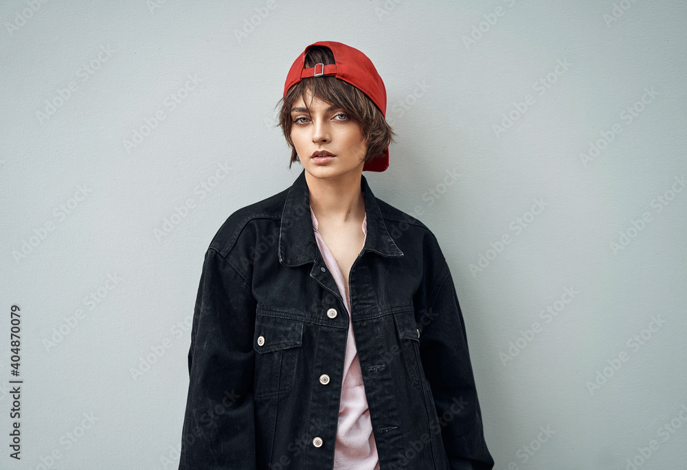 Portrait of young woman in a red Cap wear denim jacket over gray background Portrait of young woman in a red Cap wear denim jacket over gray background