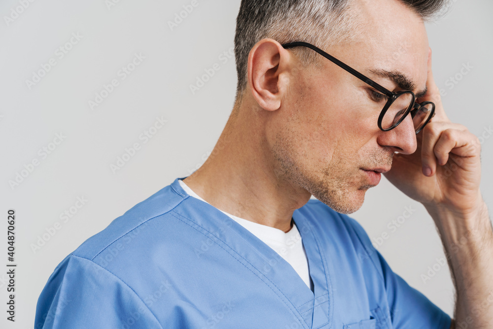 Puzzled white-haired medical doctor thinking and posing at camera Puzzled white-haired medical doctor thinking and posing at camera