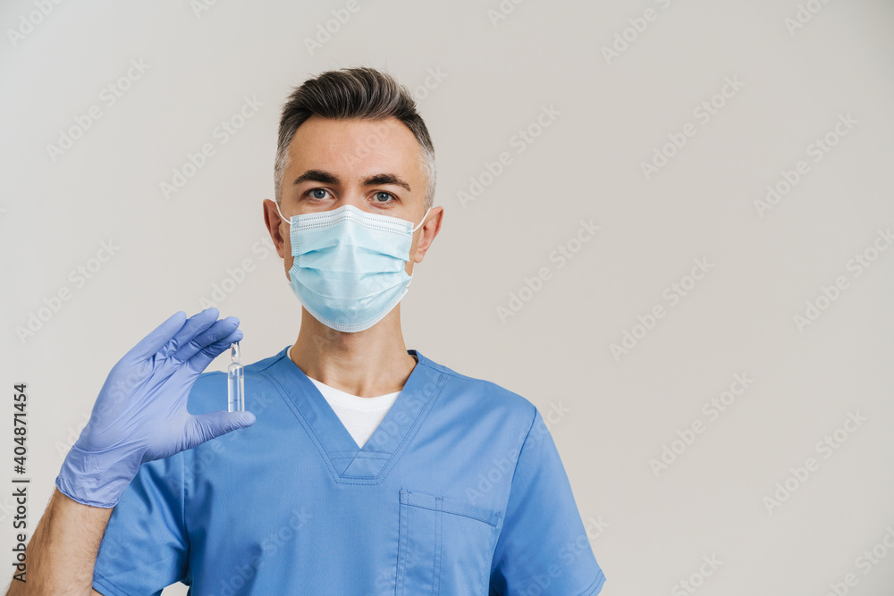 Medical doctor in face mask and gloves posing with cure vial Medical doctor in face mask and gloves posing with cure vial