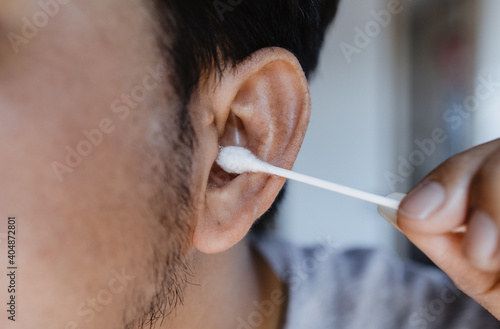 Close-up man cleaning ear with cotton bud photo